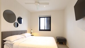 A bedroom with a bed, a ceiling fan, a window, and a TV mounted on the wall. - Comfy 2-bedroom Apartment With a Clyde River View (Batemans Bay)