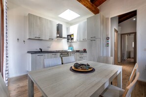 Una cucina moderna con mobili in legno chiaro, un lucernario e un'area pranzo con tavolo apparecchiato per due persone.