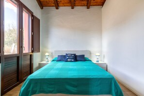 Camera da letto con un letto, due comodini, una finestra e travi in legno al soffitto.