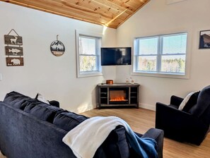 Ein Wohnzimmer mit Kamin, Fernseher und einer Couch.