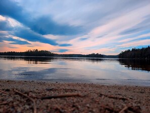 A calm lake with a forested shoreline and a clear sky. - Peaceful Lakeside Cottage with Fire Pit & Screened Porch near Flanders Pond in Sullivan, Maine (Sullivan)