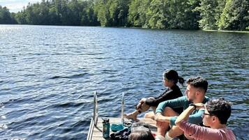 Un groupe de personnes est assis sur une jetée en bois au bord d’un lac, avec des arbres en arrière-plan.