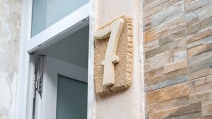 Huisnummer zeven op een ruwe stenen muur.
