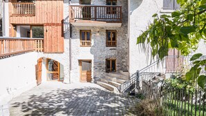 A stone building with wooden balconies and a cobblestone courtyard. - La Maison - Chalet DDA La Combe (Saint Martin de Belleville)