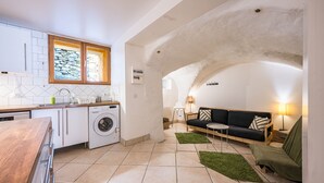 A compact living space with a kitchen, washing machine, sofa, and lamp. - La Maison - Chalet DDA La Combe (Saint Martin de Belleville)