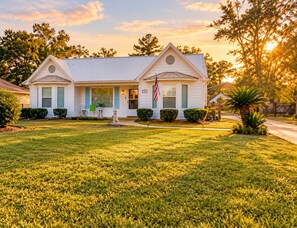 A two-story house with a front porch, a flag, and a well-maintained lawn.