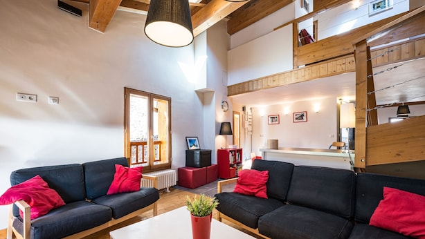 A spacious living area with a high ceiling, wooden beams, and a cozy seating arrangement. - Le Grenier - Chalet DDA La Combe (Saint Martin de Belleville)