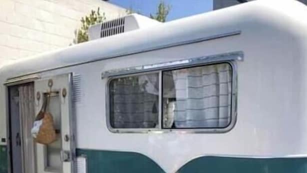 A vintage camper with a small table and two chairs outside.