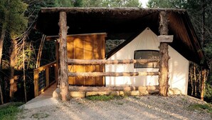 A rustic wooden cabin with a wooden deck and a white exterior.