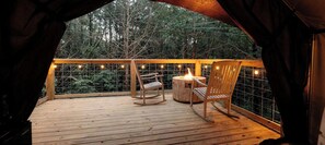 An enclosed wooden deck with a table and chairs, surrounded by a wire mesh fence and string lights. - Unique Treehouse Tent Ideal for Couples in Branson, Missouri (Branson)