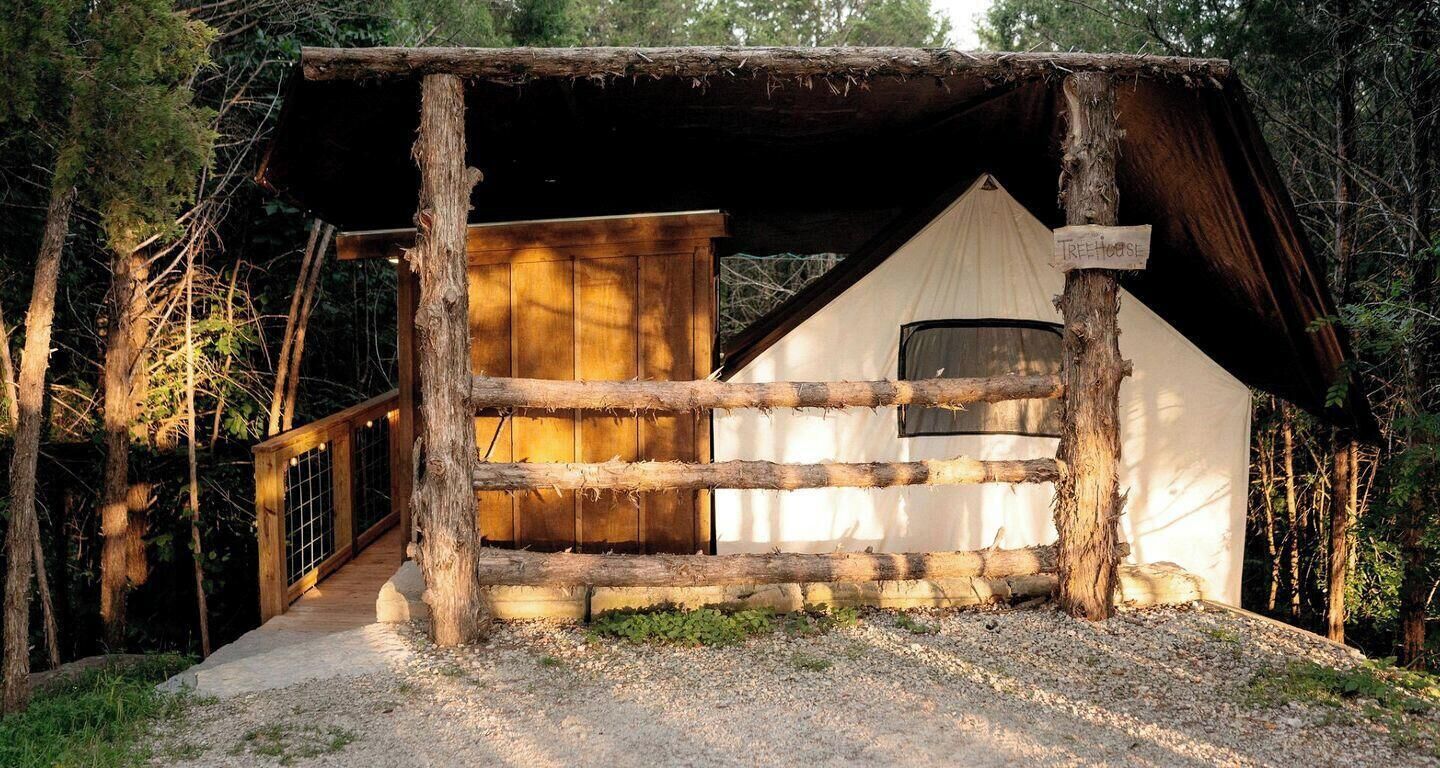A rustic cabin with a wooden deck, a large door, and a window.