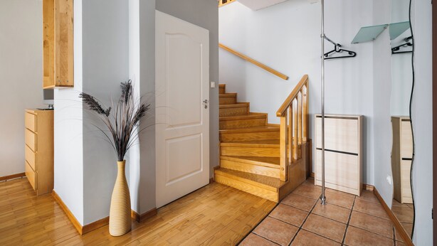 A modern interior with a wooden staircase, a white door, and a vase with dried plants. - Native Apartments Warszauera 3 (Kraków)