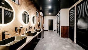 A modern bathroom with multiple sinks, round mirrors, and a wooden accent wall.