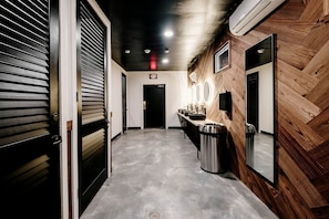 A hallway with a wooden wall, a trash bin, a sink area, and an exit sign. - Idyllic Safari Tent with Sauna and Amazing Views in North Woodstock, New Hampshire (North Woodstock)