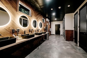 A modern bathroom with multiple sinks, mirrors, and a wooden wall design.
