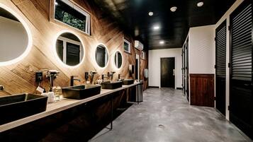 Ein modernes Badezimmer mit mehreren Waschbecken, Spiegeln und einer Wandgestaltung aus Holz.