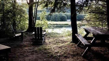 A campsite with a picnic table, a bench, and a chair.