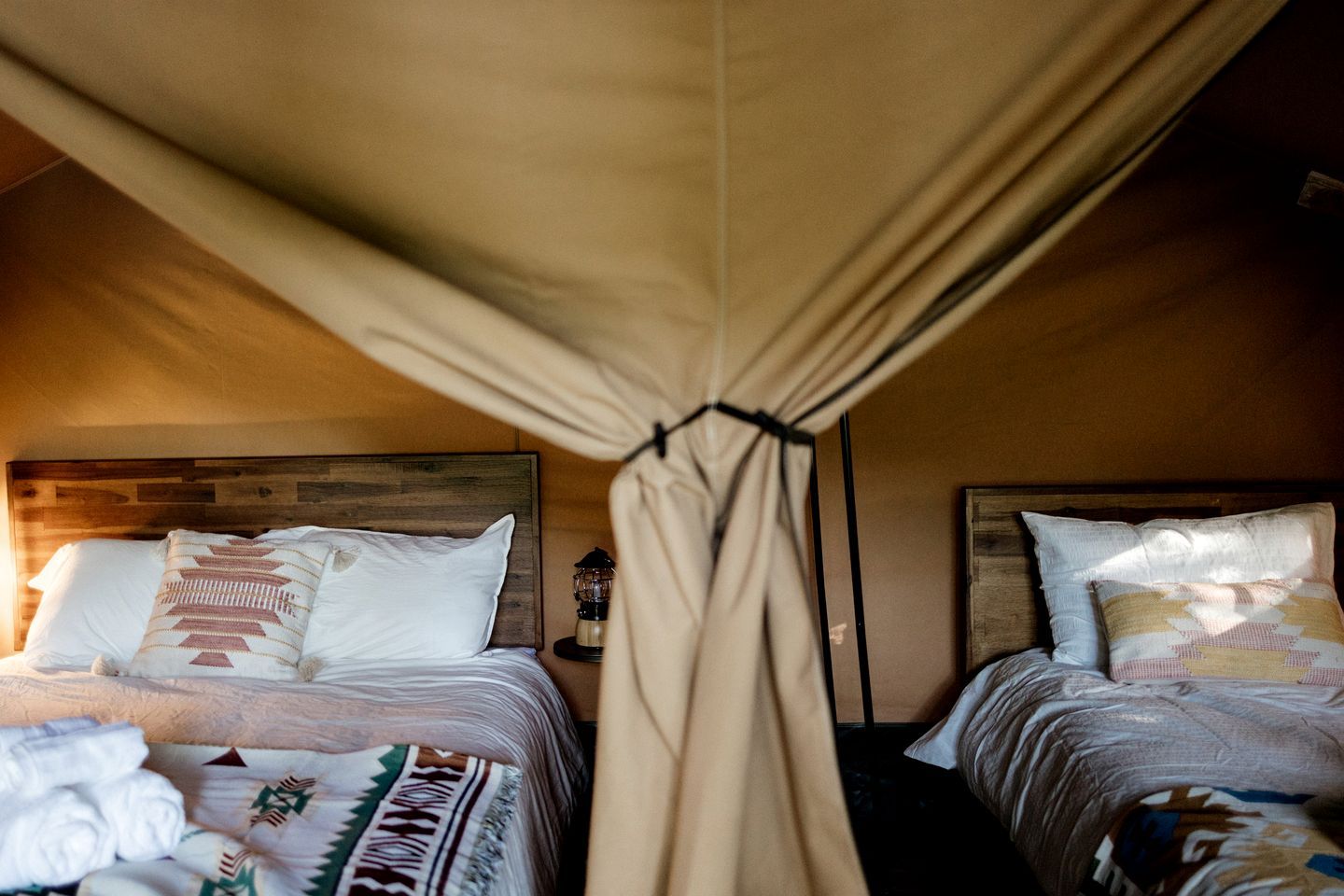 A room with two beds, each with a canopy, and a nightstand with a lamp.