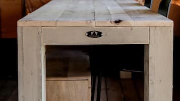 A wooden table with a drawer, set in a tent with a view of trees.