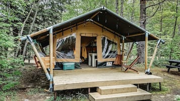 A wooden cabin with a covered porch, a picnic table, and a bench.