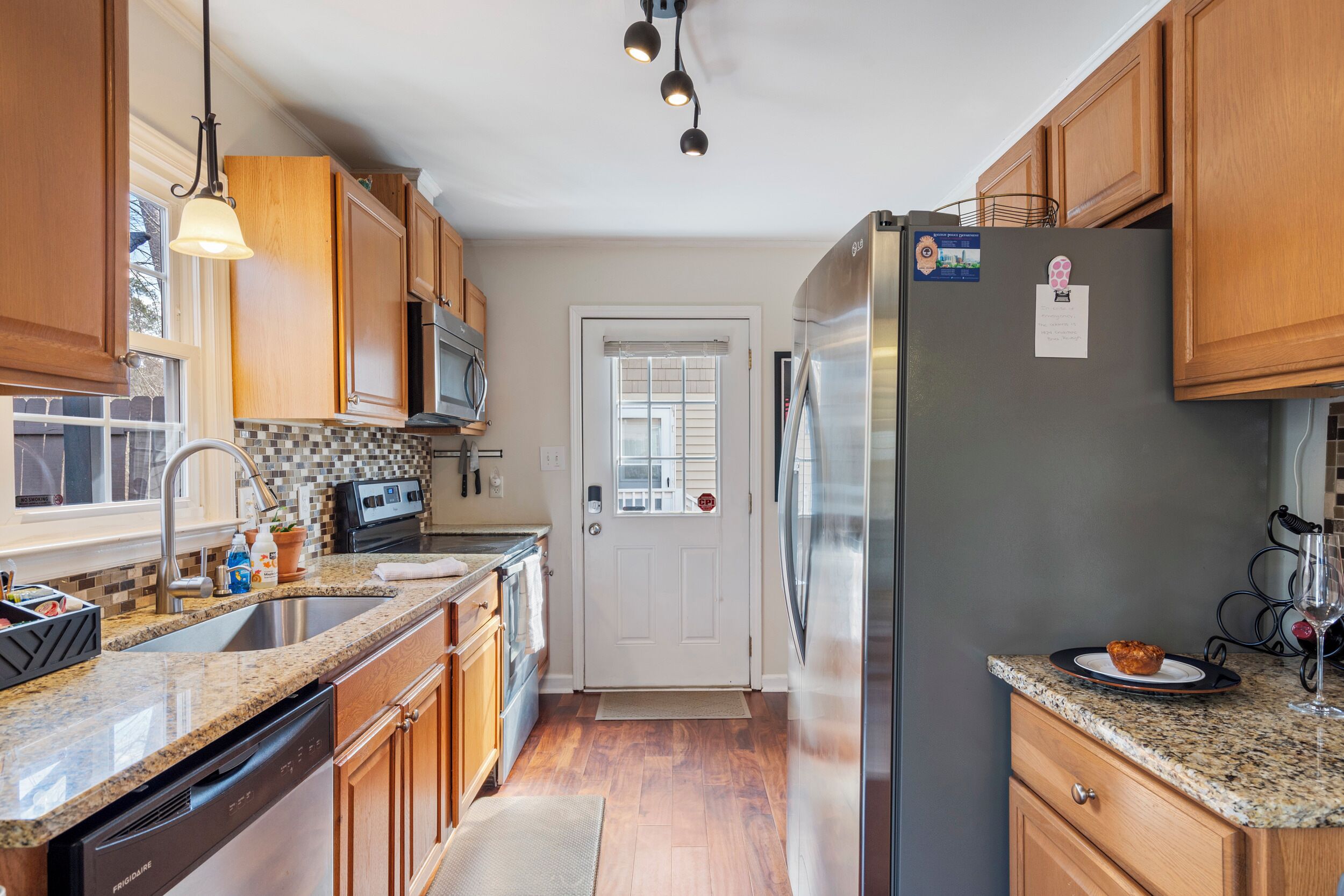 A kitchen with wooden cabinets, a stainless steel refrigerator, a microwave, and a dishwasher.