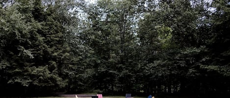 Un espacio cubierto de césped con varias sillas Adirondack y una mesa de picnic.