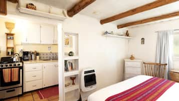 Ein kleines Zimmer mit Küchenzeile, einem Bett und einer Sitzecke.