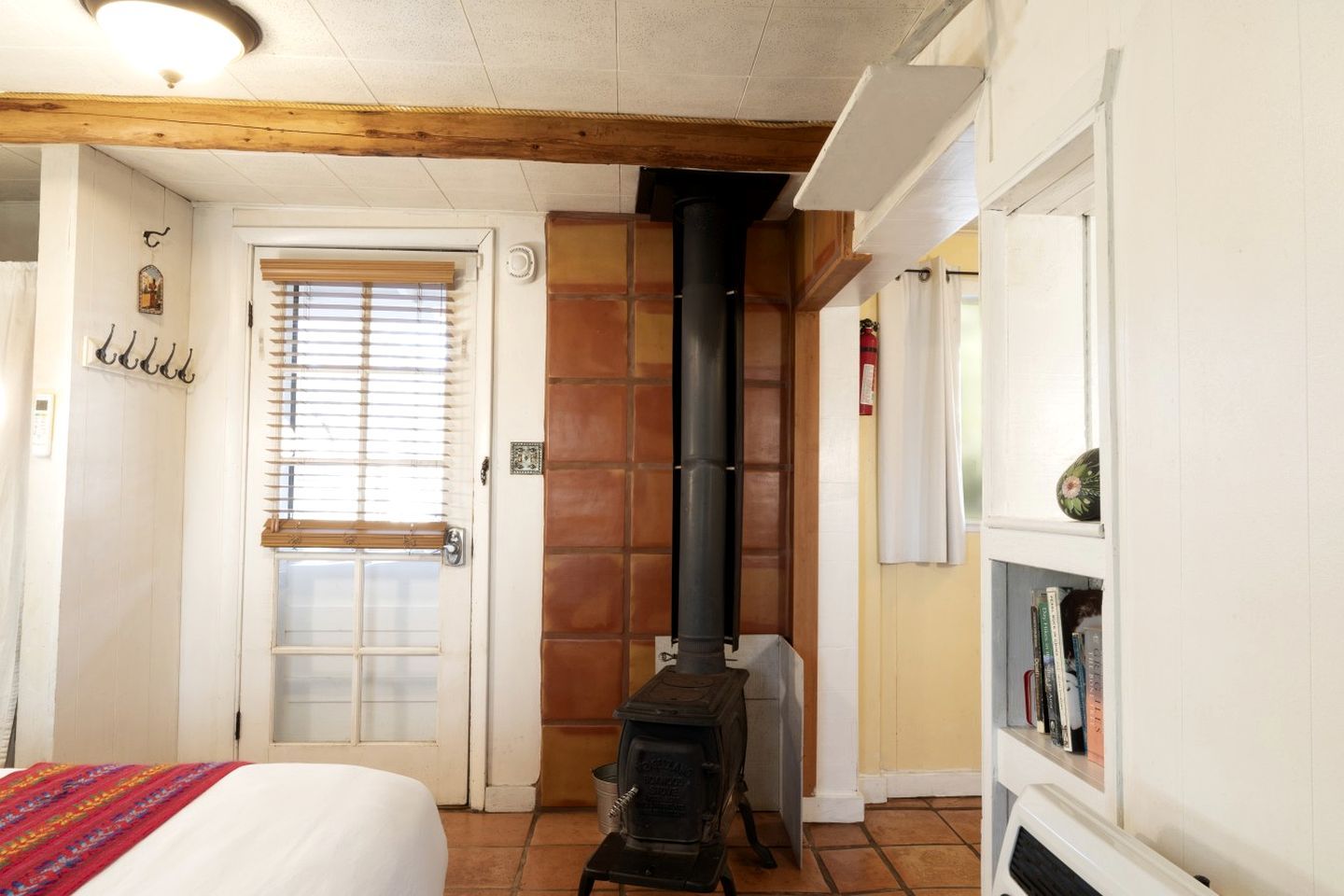 Une pièce avec un lit, une cheminée, une porte avec une fenêtre et une bibliothèque.