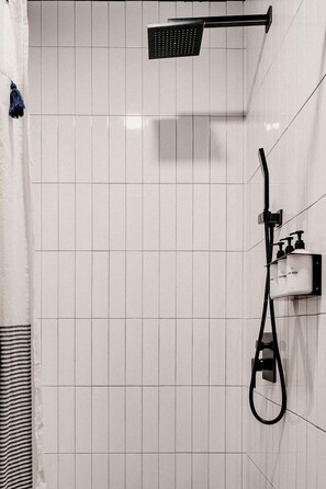 Een douche met een handdouche, een wandmengkraan en een zeepdispenser.