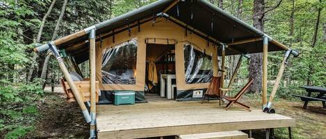 A wooden cabin with a covered porch, a picnic table, and a bench.