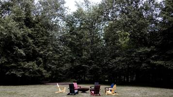 A grassy area with several Adirondack chairs and a picnic table.
