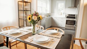 A dining table set with plates, cutlery, and a vase of flowers.