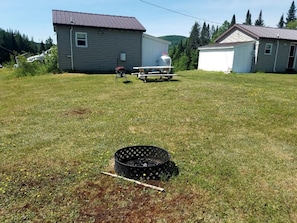 A grassy yard with a metal grill and a black circular object. - Cabin for Couples, Perfect for a Romantic Getaway in New Hampshire (Stewartstown)