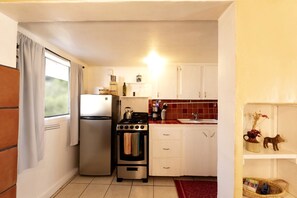 A compact kitchen with a refrigerator, stove, and sink.