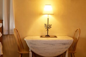 A table with a lamp and two chairs in a room with yellow walls.