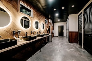 A modern bathroom with multiple sinks, mirrors, and a wooden wall design. - Charming Safari Tent with Sauna and Fire Pit in North Woodstock, New Hampshire (North Woodstock)