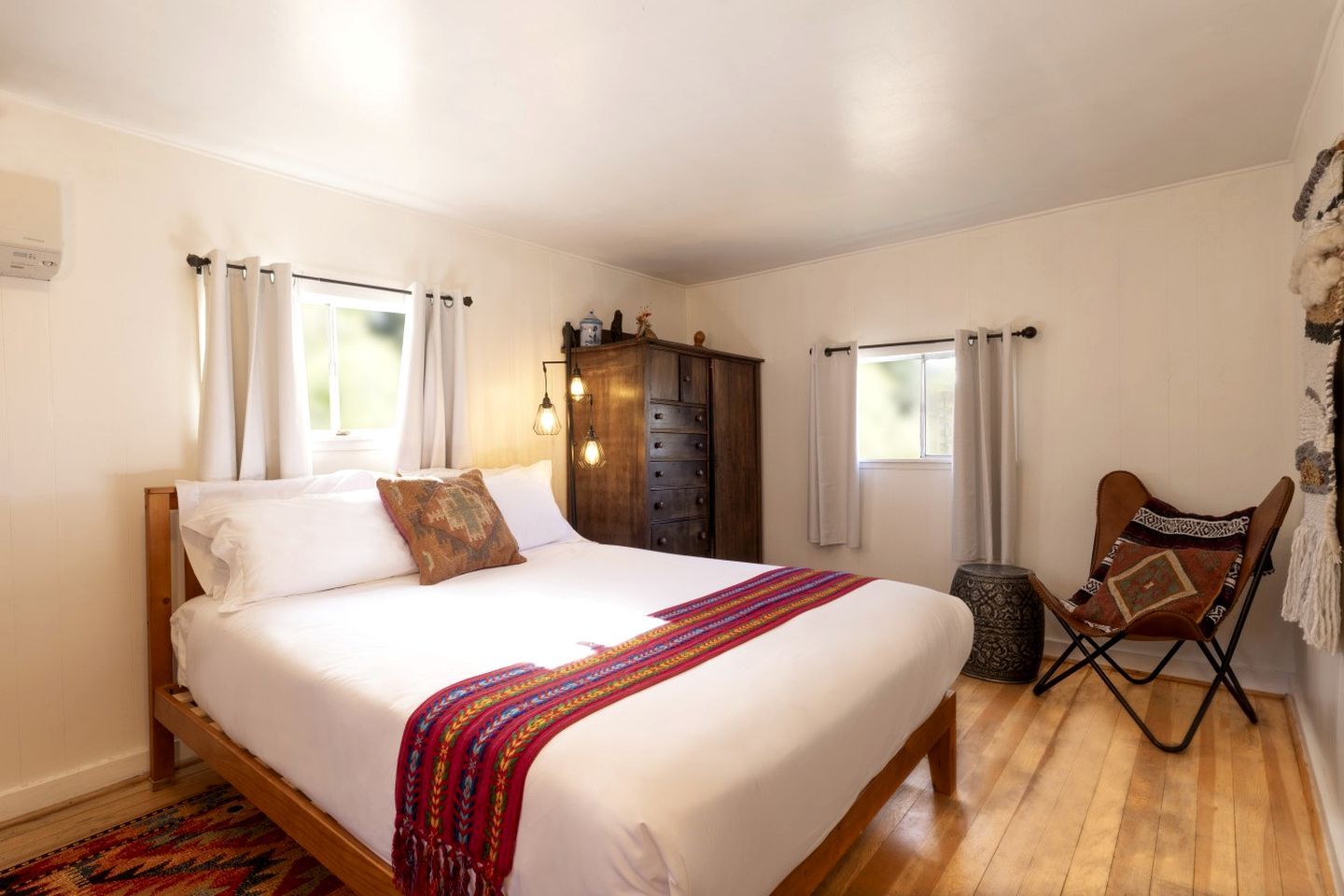 Un dormitorio con una cama, un armario de madera, una silla y una ventana.