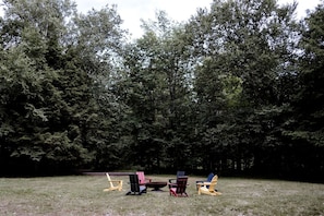 A grassy area with several Adirondack chairs and a picnic table.