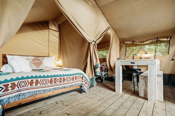 Una habitación con carpa, una cama, una mesita y una ventana.