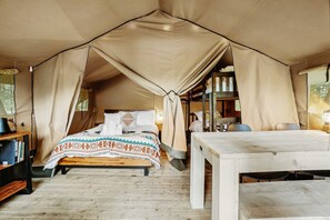 Une pièce aménagée avec une tente, un lit, une table et une chaise.