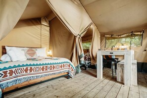 A tented room with a bed, a small table, and a window. - Lakefront Safari Tent with Fire Pit and Sauna in North Woodstock, New Hampshire (North Woodstock)