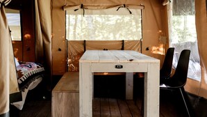Une tente avec une table, un banc et des chaises en bois.