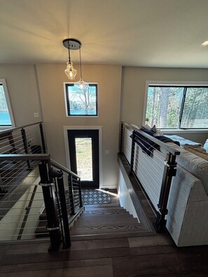 A staircase leading to a bedroom with a view of trees through a window.