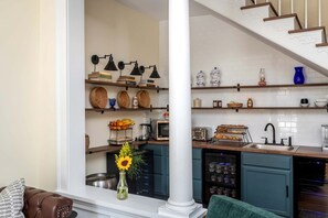 A kitchen with shelves, a toaster, a sink, and a vase with flowers.
