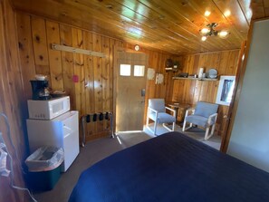 Une chambre comprenant un lit, un four à micro-ondes, un réfrigérateur, une chaise et une petite table.