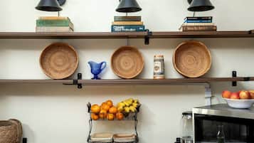 A kitchen with shelves holding books, woven baskets, and a fruit basket.