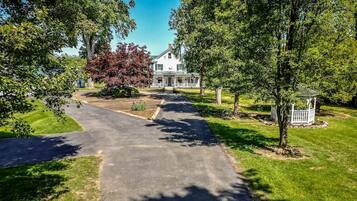 A residential property with a paved driveway leading to a white house with a green roof.