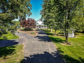 A residential property with a paved driveway leading to a white house with a green roof.