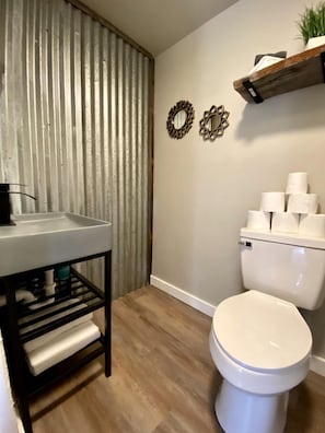 A bathroom with a white toilet, a sink with a black frame, and decorative wall mirrors.