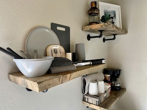 A kitchen with wooden shelves holding various kitchenware and a coffee maker. - Tiny Cabin with Beautiful Lake Views in Rapid City, South Dakota (Rapid City)
